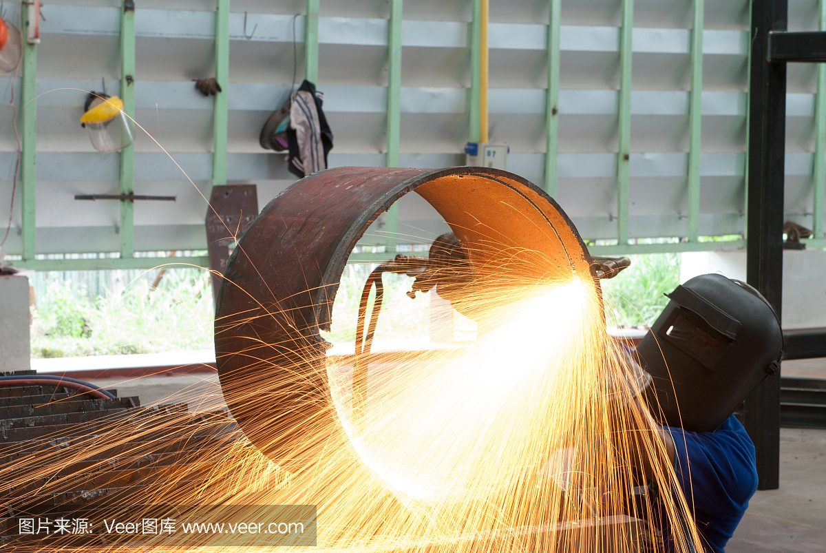 工厂里的工人用金属炬切割钢管